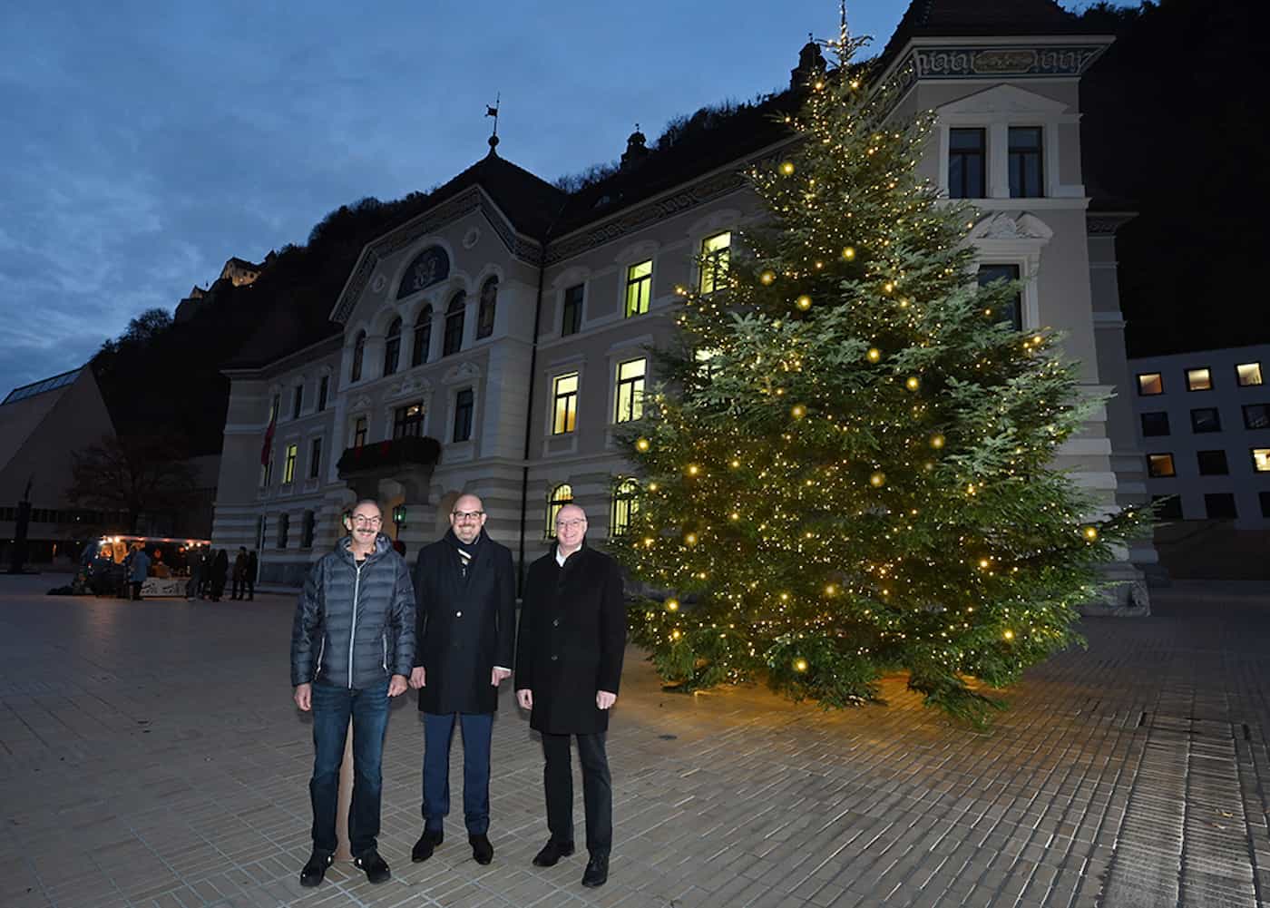 Walter Gantner Gemeinde Planken, Regierungschef Daniel Risch und Rainer Beck, Vorsteher der Gemeinde Planken bei der Übergabe des Weihnachtsbaums vor dem Regierungsgebäude. 